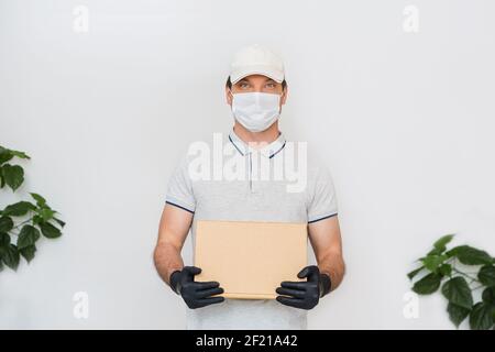 Kurier in medizinischen Gummihandschuhe und Schutzmaske hält Kartons. Türzustellung. Essen zum Mitnehmen. Lieferservice. Quarantäne. Coronavirus. Stockfoto
