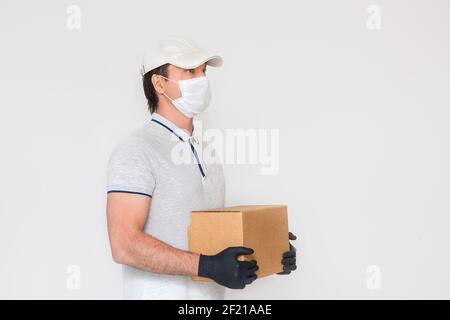 Kurier in medizinischen Gummihandschuhe und Schutzmaske hält Kartons. Türzustellung. Essen zum Mitnehmen. Lieferservice. Quarantäne. Coronavirus. Stockfoto
