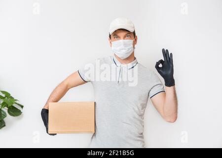 Kurier in medizinischen Gummihandschuhe und Schutzmaske hält Kartons. Türzustellung. Essen zum Mitnehmen. Lieferservice. Quarantäne. Coronavirus. Stockfoto