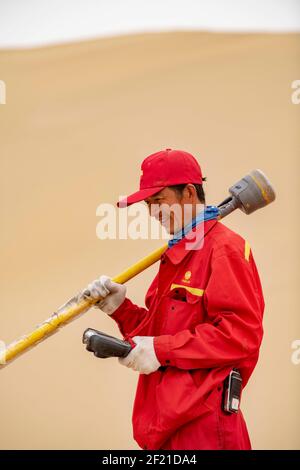 (210310) --URUMQI, 10. März 2021 (Xinhua) -- Feng Yongsheng vom geophysikalischen Untersuchungsteam arbeitet in der Taklimakan-Wüste, nordwestlich der Autonomen Region Xinjiang Uygur in China, 25. Februar 2021. Die Taklimakan-Wüste im Tarim-Becken der Autonomen Region Xinjiang Uygur im Nordwesten Chinas ist eine der größten petroliferösen Regionen Chinas und aufgrund ihrer rauen Bodenbedingungen und der komplizierten unterirdischen Bedingungen eine der schwierigsten zu erkunden. Die Erkundung der Öl- und Gasressourcen erfordert mehrere Prozesse, einschließlich der Durchführung geophysikalischer Untersuchungen, um seismische Daten zu sammeln, um dies zu ermöglichen Stockfoto