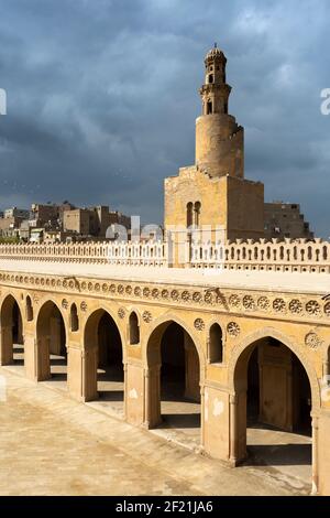 Die Moschee von Ibn Tulun mit Minarett und Bögen unter dunklen Sturmwolken, in Tolon, El-Sayeda Zainab, Kairo, Ägypten Stockfoto