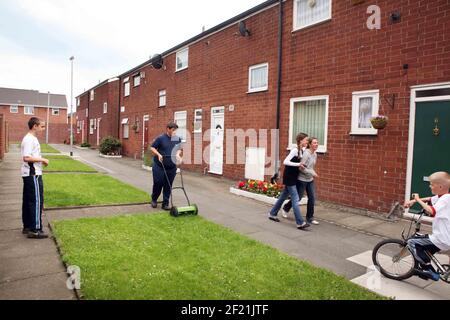 Newton Heath in Manchester Vorbereitung auf die Beurteilung in Großbritannien in Bloom Competition Rasenmähen Gemeinschaft...Michael Garnet Sohn von Marlene Garnett, die mit Hilfe von lokalen Volenteer Kinder (ECO JUGEND) verbringen viele Stunden auf die Pflege der Gärten, Hängekörbe etc. In Newton Heath Bild David Sandison Stockfoto