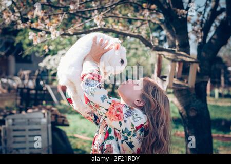 Liebenswert schöne Mädchen mit langen blonden Haaren umarmt weißen Ostern Kaninchentier Stockfoto