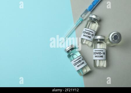 Fläschchen mit COVID-19-Impfstoff und eine Spritze auf einem zweifarbigen Hintergrund, Impfkonzept Stockfoto