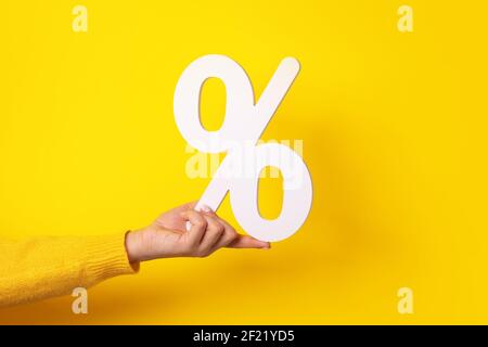 Hand hält Prozentzeichen über gelbem Hintergrund Stockfoto