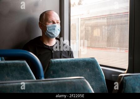 Serious Mann trägt chirurgische Maske Blick durch das Fenster in Ein Zug Stockfoto