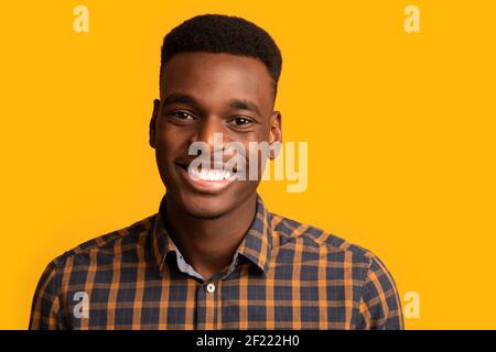 Nahaufnahme Porträt von positiven jungen afroamerikanischen Kerl aufrichtig lächelnd Bei der Kamera Stockfoto