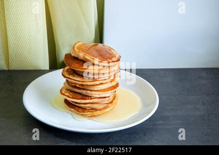 Süße hausgemachte Pfannkuchen auf einem Teller mit Honig. Stockfoto