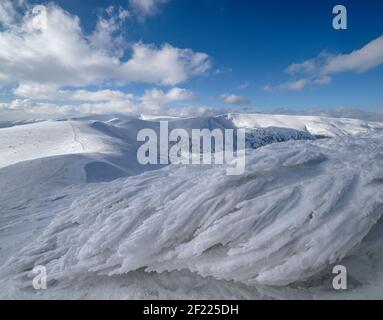 Schnee und Wind bildeten Eisformationen bedeckten Winter-Bergplateau, Gipfel mit Schnee Gesimse in der Ferne. Herrlicher sonniger Tag auf pi Stockfoto