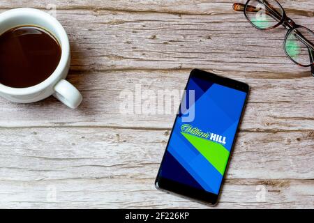 Ein Mobiltelefon oder Mobiltelefon auf einem Tisch Oder Schreibtisch mit der William Hill App geöffnet und ein Kaffee daneben Stockfoto