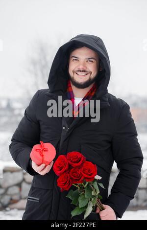 Schöner romantischer junger Mann mit Strauß roter Rosen in Hände Stockfoto