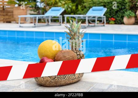 Tropische Früchte liegen in einem Korb auf dem Hintergrund des blauen Schwimmbades. Stockfoto