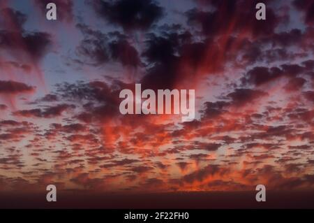 Fantastischer Anblick eines Abendhimmels in verschiedenen Schattierungen Rote und viele kleine Wolken Stockfoto