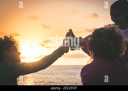 Grüße an die besten Freunde, Freunde genießen Getränke am Abend am Strand bei Sonnenuntergang. Hände, die Flaschen Bier halten. Konzept der Ferienhäuser, Pflege Stockfoto