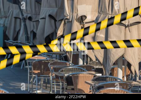 Leere Tische mit Schirmen im Restaurant auf der Straße bei Sonnenaufgang. Stockfoto