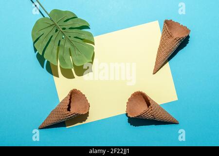 Tropisches Palmenblatt mit Eiszapfen auf hellblauem Hintergrund. Minimale Zusammensetzung für den Sommer. Flach liegend. Stockfoto