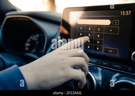 Teenager fahren ein Auto und nutzen Infotainment. Junger Mann liest Nachrichten und telefonieren während der Fahrt. Gefährliches Verhalten, Unfallgefahr. Gefahr, Transg Stockfoto