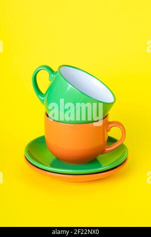 Zwei bunte leere Teetassen und Untertassen. Satzgeschirr, eine Sammlung von Kaffeetassen, ein Set von Tassen. Keramik bemalte Utensilien auf einem gelben Hintergrund Stockfoto