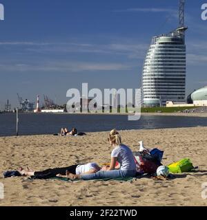 Menschen am Weser Strand Bad mit dem Atlantic Hotel Sail City im Hintergrund, Bremerhaven, Deutschland Stockfoto