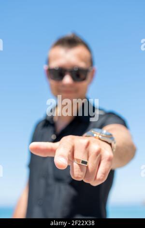 Glücklicher Mann, der mit dem Finger auf die Kamera am Himmel zeigt. Selektiver Fokus. Stockfoto