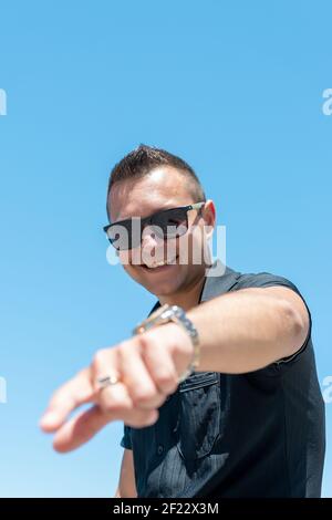 Glücklicher Mann zeigt die Finger auf die Kamera am Himmel Hintergrund. Stockfoto