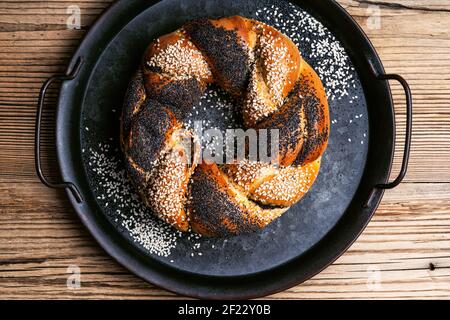 Hausgemachtes Osterbrot Ring mit Mohn und Sesam auf Vintage-Tablett auf rustikalem Holzhintergrund, Draufsicht dekoriert Stockfoto