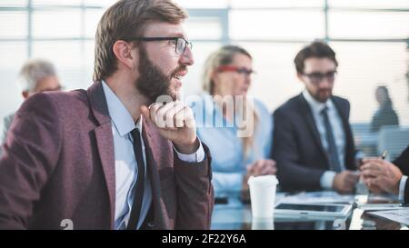 Nahaufnahme. Selbstbewusster junger Unternehmer sitzt an seinem Schreibtisch. Stockfoto