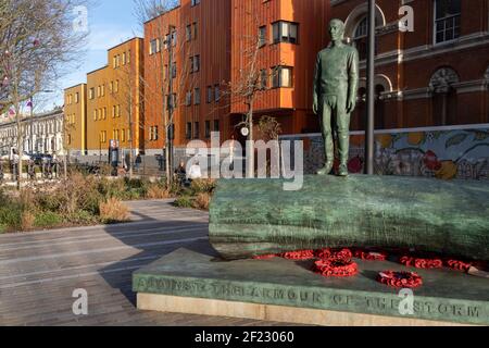 Die Bronzeskulptur eines Jungen ist Teil des Kunstwerks von Kenny Hunter am Walworth Square at Elephant and Castle am 9th. März 2021 in London, England. Die vollständige Inschrift lautet: „Gegen die Rüstung des Sturms halte ich meine menschliche Barriere fest“ – eine Zeile aus einem Gedicht aus dem Zweiten Weltkrieg von Hamish Henderson. Das eindrucksvolle Bronzekunstwerk wurde im Jahr des 100. Jahrestages des Waffenstillstands und des Endes des Ersten Weltkriegs installiert. Die Skulptur wurde beauftragt, an alle Leben zu erinnern, die von Krieg und Konflikten auf der ganzen Welt betroffen sind, einschließlich des Lebens von Mitgliedern des A Stockfoto