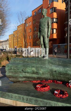 Die Bronzeskulptur eines Jungen ist Teil des Kunstwerks von Kenny Hunter am Walworth Square at Elephant and Castle am 9th. März 2021 in London, England. Die vollständige Inschrift lautet: „Gegen die Rüstung des Sturms halte ich meine menschliche Barriere fest“ – eine Zeile aus einem Gedicht aus dem Zweiten Weltkrieg von Hamish Henderson. Das eindrucksvolle Bronzekunstwerk wurde im Jahr des 100. Jahrestages des Waffenstillstands und des Endes des Ersten Weltkriegs installiert. Die Skulptur wurde beauftragt, an alle Leben zu erinnern, die von Krieg und Konflikten auf der ganzen Welt betroffen sind, einschließlich des Lebens von Mitgliedern des A Stockfoto