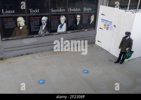 Ein sozial distanzierter Busfahrer trägt eine Gesichtsbedeckung, während er auf den nächsten Dienst wartet, und die berühmten Wissenschaftler, die am University College London (UCL), am Strand im Zentrum von London, am 8th. März 2021, in London, England, studiert haben. King's College London ist eine öffentliche Forschungsuniversität in London, Großbritannien, und eine Gründungshochschule und Mitgliedsinstitution der Universität London. Stockfoto