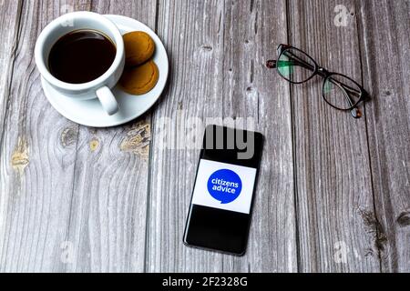 Ein Handy oder Handy auf einem Holz gelegt Tabelle mit dem Logo des Bürgerberatungs-Büros auf dem Bildschirm Stockfoto