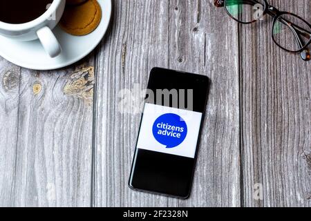 Ein Handy oder Handy auf einem Holz gelegt Tabelle mit dem Logo des Bürgerberatungs-Büros auf dem Bildschirm Stockfoto