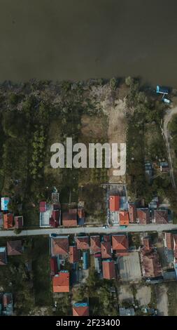 Ein Blick von oben auf die Flussküste und eine einspurige Straße umgeben von Feldern und kleinen Gebäuden Stockfoto