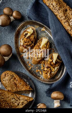 Stillleben Bild von leckeren und gesunden Bruschetta oder Sandwich mit geröstetem Knoblauch und Champignon Pilze auf dem blauen, tex Stockfoto