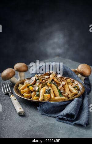 Pasta Penne mit gerösteten Pilzen, Knoblauch und Zucchini. Italienische Küche auf blauem Marmortisch. Stockfoto