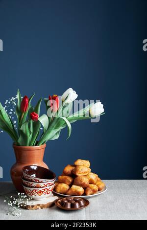 Kasachische Nationalschalen Kese, gebratenes Brot baursaks und Tulpen während Nauryz Festival auf blauem Hintergrund Stockfoto