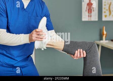 Physiotherapeut, der Beinverletzungen bei einer älteren Frau behandelt, die sich im Nahbereich hinlegt Stockfoto