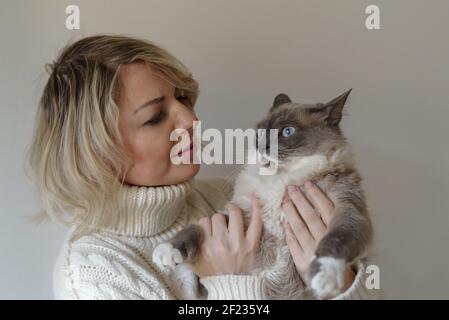 Nahaufnahme einer Frau, die ihre siamesische Katze in der Halle umarmt Stockfoto