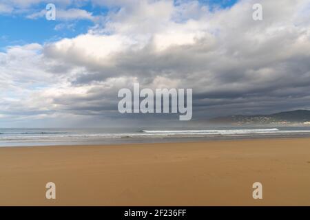 Leerer und großer schöner goldener Sandstrand unter einem schlechten Wetterhimmel Stockfoto