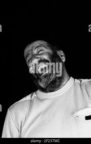 Porträt eines lachenden grauen bärtigen Armeniers auf einem dunklen Graues Schwarz-Weiß-Foto mit Hintergrund Stockfoto