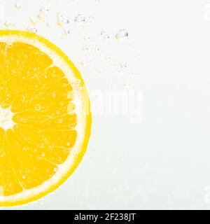 Nahaufnahme einer Scheibe Orange in Sodawasser mit Blasen. Sommerdrink-Konzept. Stockfoto