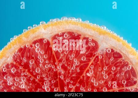 Nahaufnahme einer Scheibe Grapefruit in Sodawasser mit Blasen. Sommerdrink-Konzept. Stockfoto