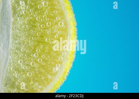 Nahaufnahme einer Kalkscheibe in Sodawasser mit Blasen. Sommerdrink-Konzept. Stockfoto