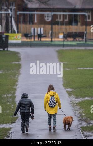 London, Großbritannien. März 2021, 10th. Das schlechte Wetter bedeutet, dass der Kinderspielplatz ungewöhnlich leer ist - es regnet und ist kalt, aber die Leute treffen sich immer noch mit Freunden und/oder bekommen etwas Bewegung. Outdoor-Leben auf Clapham Common gegen Ende der Lockdown 3. Kredit: Guy Bell/Alamy Live Nachrichten Stockfoto