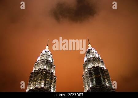 Nahaufnahme der Petronas Twin Towers bei Nacht Mit beleuchteter oranger Wolke Stockfoto