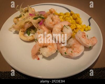 Seafood Salat auf einem Teller serviert. Teller mit gesunden Lebensmitteln. Gegrillte Garnelen, Calamari und Mais. Stockfoto