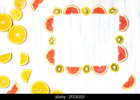 Eine Draufsicht auf einen Rahmen mit Grapefruit und Kiwi Scheiben und orangefarbene Scheiben auf dem weiß-blauen Hintergrund Stockfoto