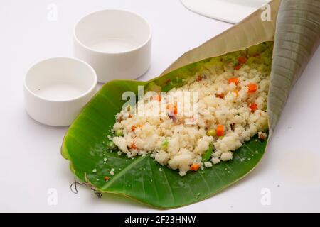 UPMA aus Samolina oder rava Upma, dem berühmtesten südindischen Frühstückselement, das wunderschön in einem Bananenblatt mit leerer kleiner Schüssel in der Nähe angeordnet ist Stockfoto