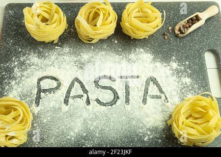 Das Wort Pasta auf einem Pasta-Hintergrund. Pasta Wort auf dem Tisch Zusammensetzung mit Zutaten geschrieben Stockfoto