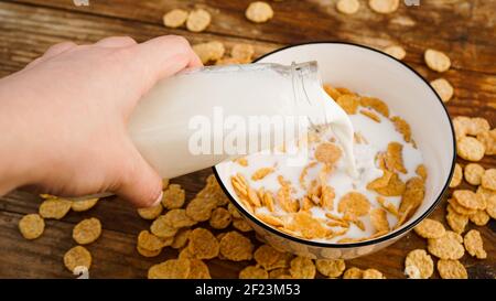 Gesunde Ernährung Hintergrund. Frische Milch in Schüssel Cornflakes gießen Stockfoto